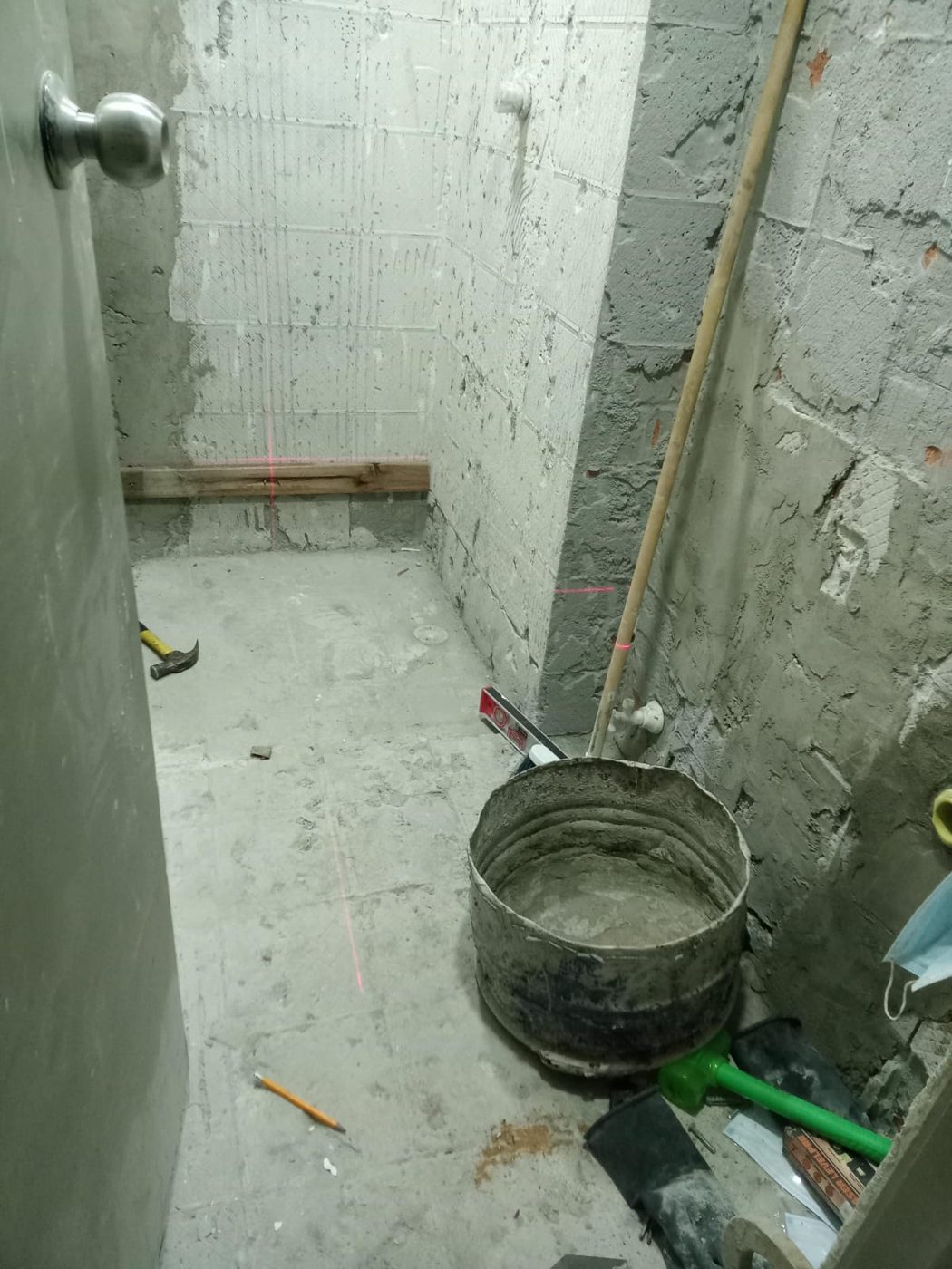 Baño en obra gris con tubería y niveles marcados